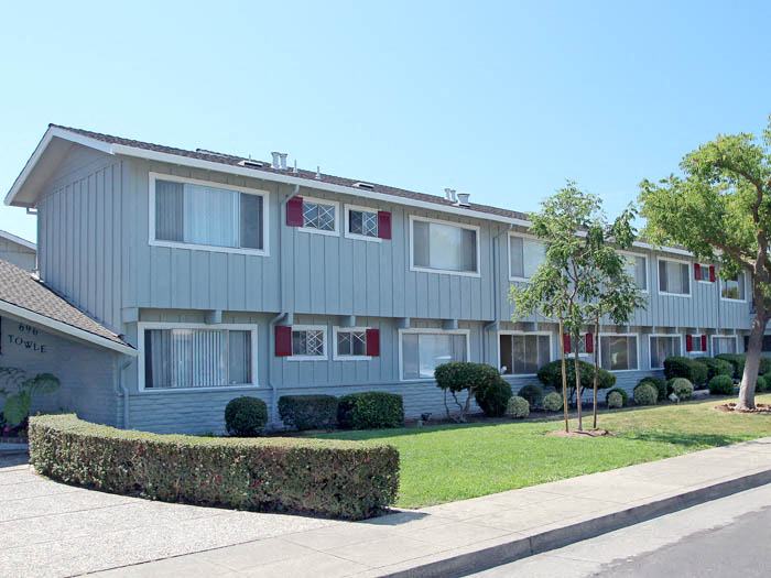an apartment building with a lawn and trees in front of it
